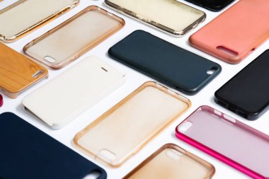 Cep telefonu için çok renkli plastik kapaklar yığını. Beyaz arka planda akıllı telefon koruyucusu aksesuarları. Bir sürü silikon telefon ve deri yan yana.