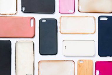 Cep telefonu için çok renkli plastik kapaklar yığını. Beyaz arka planda akıllı telefon koruyucusu aksesuarları. Bir sürü silikon telefon ve deri yan yana.