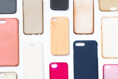 Cep telefonu için çok renkli plastik kapaklar yığını. Beyaz arka planda akıllı telefon koruyucusu aksesuarları. Bir sürü silikon telefon ve deri yan yana.