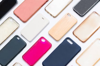 Cep telefonu için çok renkli plastik kapaklar yığını. Beyaz arka planda akıllı telefon koruyucusu aksesuarları. Bir sürü silikon telefon ve deri yan yana.