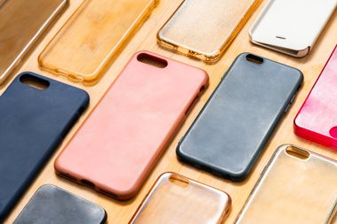 Cep telefonu için çok renkli plastik kapaklar yığını. Ahşap arka planda akıllı telefon koruyucusu aksesuarları seçimi. Arka arkaya bir sürü silikon telefon ya da deri, desen.