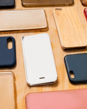 Cep telefonu için çok renkli plastik kapaklar yığını. Ahşap arka planda akıllı telefon koruyucusu aksesuarları seçimi. Arka arkaya bir sürü silikon telefon ya da deri, desen.