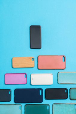 Mavi arka planda cep telefonları için çok renkli plastik kapak yığını.