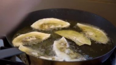 Close up of chefs hand placing Gyoza dumplings with mushroom filling into hot frying pan. Golden crunchy dumplings cooking in oil. 