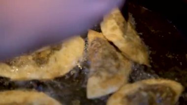 Şef 'in Gyoza hamur köftelerini mantarla çevirerek sıcak tavayı doldurmasına yakın çekim. Yağda pişen altın çıtır börekler.. 