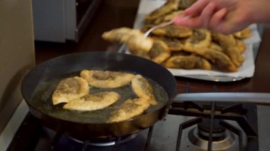 Şef 'in Gyoza hamur köftelerini mantarla çevirerek sıcak tavayı doldurmasına yakın çekim. Yağda pişen altın çıtır börekler.. 