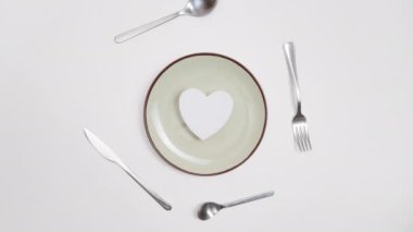 Romantik Sevgililer Günü yemeği fikri. Kalp tabakta, gümüş aşınma da kırmızı zeminde. Hareketi durdur. 