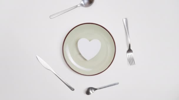 ロマンチックなバレンタインの一日のディナーのアイデアのコンセプト 赤の背景にプレートと銀の摩耗に心臓 ストップモーションアニメーション — ストック動画