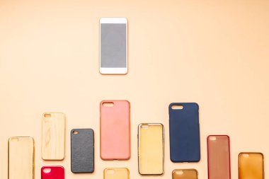 Tarafsız arka planda cep telefonları için çok renkli plastik kapaklar ve yanında da akıllı bir telefon seçeneği.