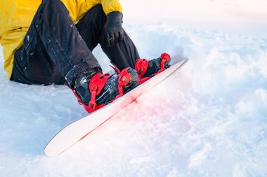 Snowboardçular tepeye tırmanmadan önce bir snowboard hazırlıyorlar..