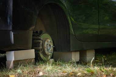 Dışarıdaki tuğlalarla arabayı kapatın. Çalıntı araç tekerleği kavramı. Tekerleği olmayan araba..