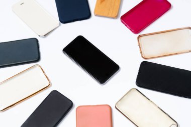 Beyaz arka planda cep telefonu için çok renkli plastik kapaklar yığını. Akıllı telefon koruyucusu aksesuarları seçimi. Akıllı telefonun yanında bir sürü silikon telefon ya da deri var.