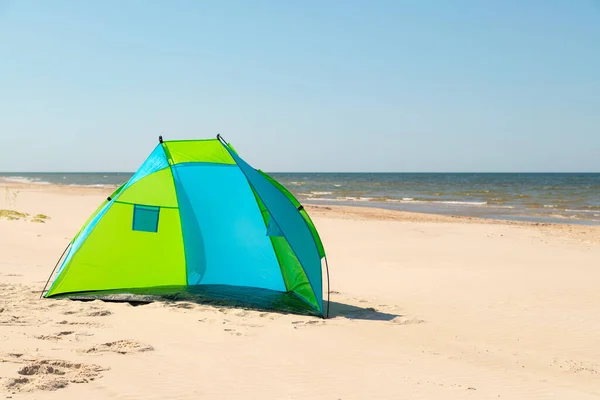 Wind breaker tent on a sandy beach by the sea. Nobody. Colorful tent protection from wind and sunburn.