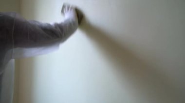 Eldivenli ve koruyucu iş elbiseli bir işçi duvarı zımparalıyor. Boya için hazırlık odası. Ev yenilenmesi. 