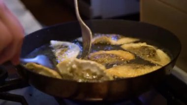 Şef 'in Gyoza hamur köftelerini mantarla çevirerek sıcak tavayı doldurmasına yakın çekim. Yağda pişen altın çıtır börekler.. 