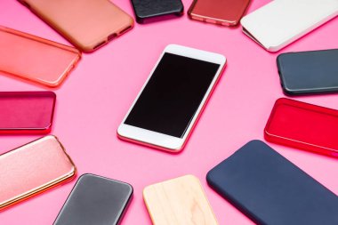 Pembe arka planda cep telefonları için çok renkli plastik arka kapaklar ve yanında akıllı bir telefon seçeneği.