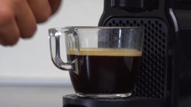 Evdeki kahve makinesinden bir fincan espresso almak için elinizi kaldırın. Kahve molası kavramı. 