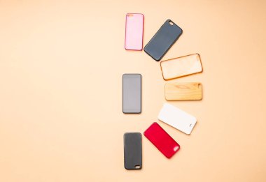 Tarafsız arka planda cep telefonları için çok renkli plastik kapaklar ve yanında da akıllı bir telefon seçeneği.