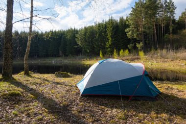 Ormandaki gölün yanında kamp çadırı kuruldu. Açık havada bir kamp alanında dinleniyor..