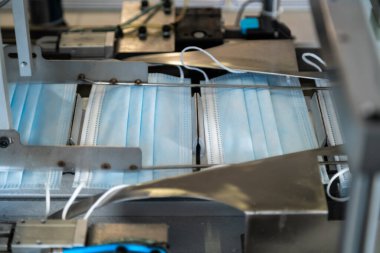 Bir fabrikada yapılan tıbbi yüz maskelerinin yakın çekim süreci. Otomatik makineler büyük miktarlarda solunum maskesi yapıyor..