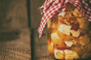 Bir kavanoz kapağı ve eski bir ahşap zemin üzerine süs kare bez ile doğal süt taze ev yapımı peynir. Film tahıl etkisi.