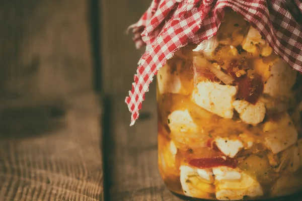 Bir kavanoz kapağı ve eski bir ahşap zemin üzerine süs kare bez ile doğal süt taze ev yapımı peynir. Film tahıl etkisi.