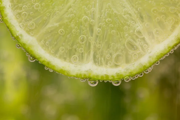 Zielone limonki z plusk wody — Zdjęcie stockowe