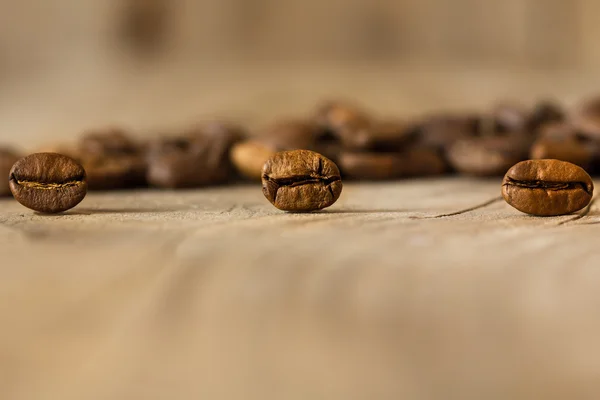 Chicchi di caffè da vicino su un vecchio tavolo di legno . — Foto Stock