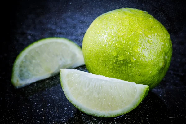 Sliced lime on a black marble desk — Stock Photo, Image