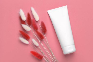 Makyaj şablonu. Kozmetik kremi. Fotokopi alanı ya da marka logosu metni için yeri olan temiz beyaz. Stüdyo, pembe arka planda doğal otlarla yakın çekim yapar..