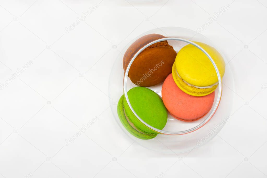 multicolored french macarons in a glass vase on a white background, top view