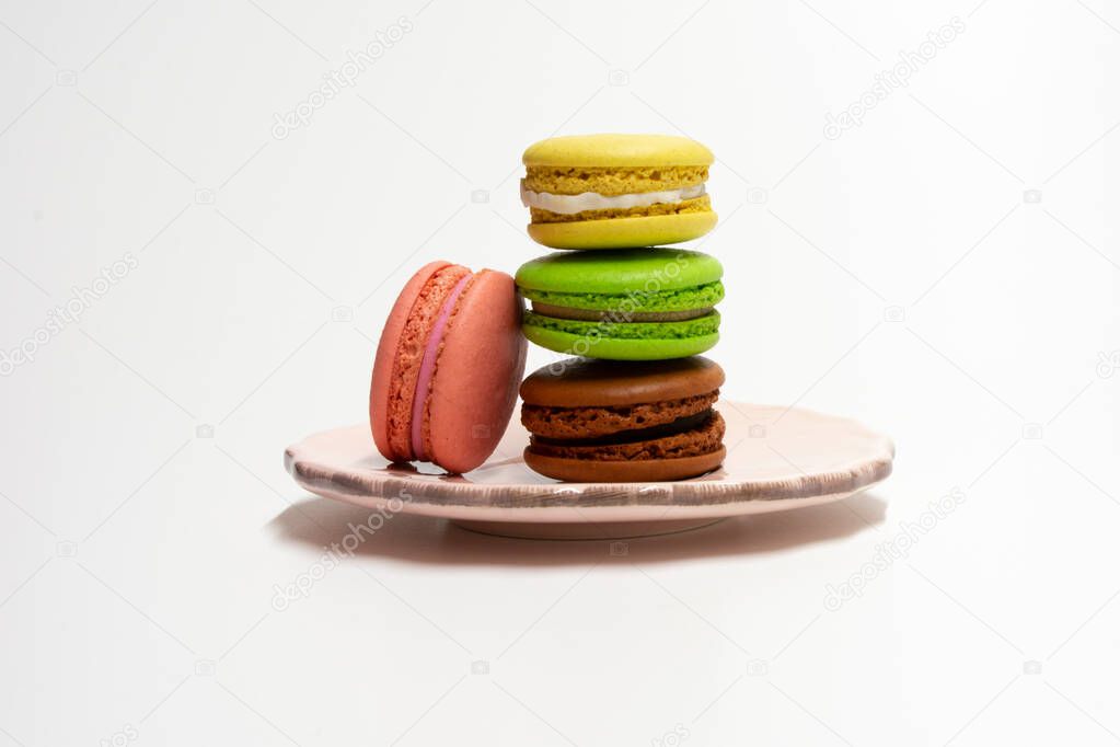 Multicolored macaroons on a pink plate on a white background