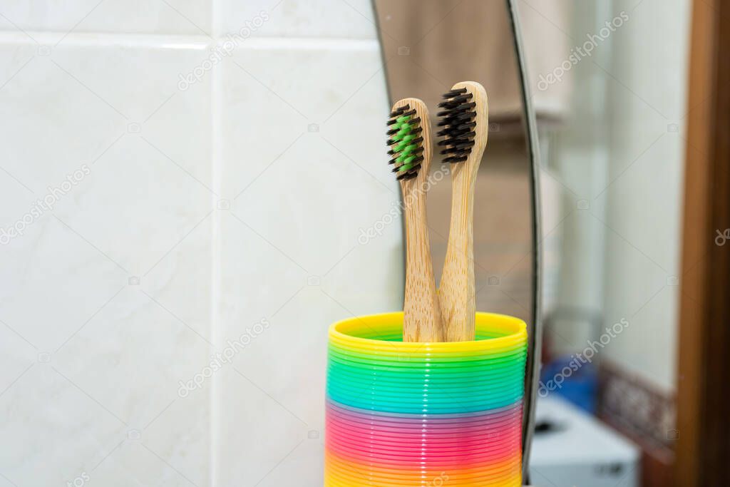 Toothbrushes in a rainbow stand near the bathroom mirror.