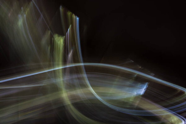 Abstract illustration with light from multi-colored curved lines on a black background. Photo effect.