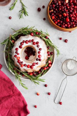 Dekor olarak pudra şekeri, kızılcık ve biberiyeli Noel pastası. Böğürtlen, peçete, çay ve süzgeç gri arka planda. Tebrik kartı.