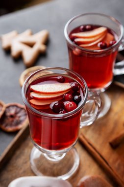 Bardağı sıcak yaban mersiniyle kapat elma dilimleri ve böğürtlenlerle süslenmiş iç. Noel ve yeni yıl içeceği mevsimlik dekorasyonlu