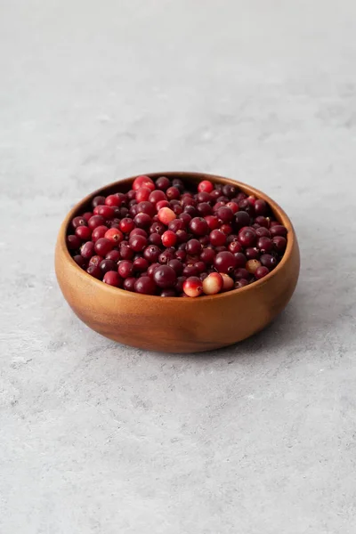 Cranberries at wooden dish at gray background