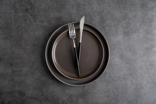 Tabaklar ve gümüş takımlar gri arkaplanda. Üst manzara, düz yatak, zarafet konsepti karanlık masa düzeni. Metin için alanı kopyala