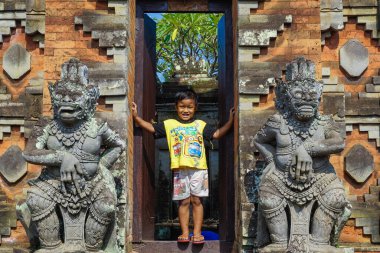 Bali, Endonezya - 10 Ocak 2019: Hindu tapınağının girişindeki genç çocuk