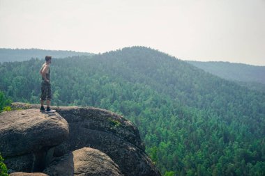 Krasnoyarsk Sütunları 'nda bir kayanın üzerinde yürüyüş yapan doğa koruyucusu.
