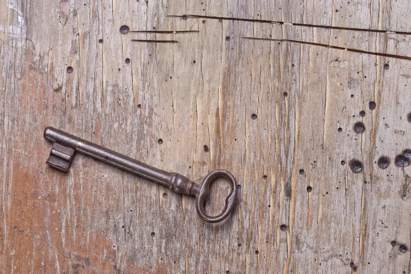 Pojedynczy klucz na starym drewnianym stole — Zdjęcie stockowe