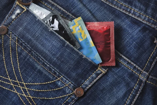 Mix van condooms in de blue jeans zak — Stockfoto