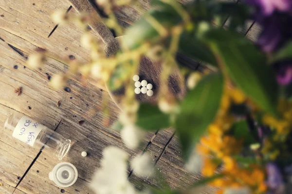 Homeopathie bolletjes tussen vervagen bloemen — Stockfoto