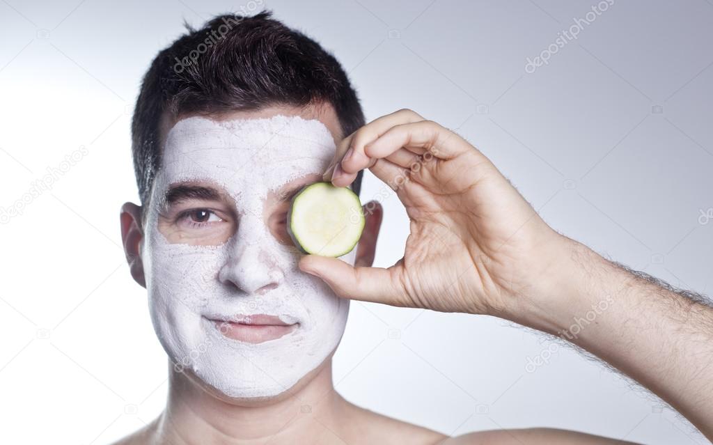 handsome man with clay facial mask in beauty spa