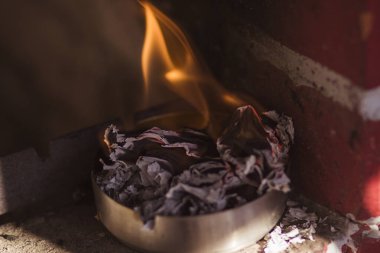 Metal bir kavanozda alev alev yanan buruşmuş bir kağıt parçası.