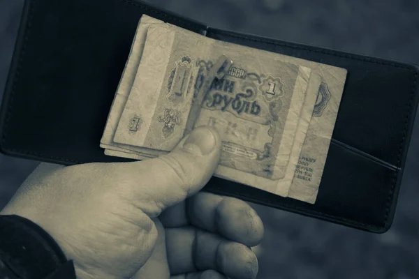 Kahverengi deri, modaya uygun bir cüzdan. Elinde Sovyet kağıt retro rublesi olan bir adam.