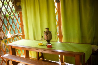 Rus bakır semaver ve çay fincanları çardaktaki masada.