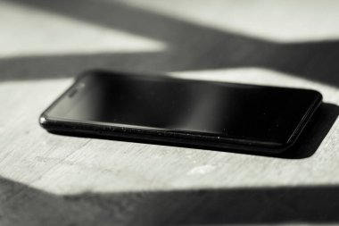 Ahşap bir masada büyük ekranlı siyah bir cep telefonu.