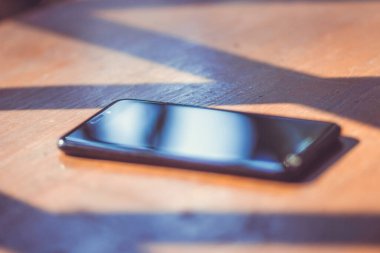 Ahşap bir masada büyük ekranlı siyah bir cep telefonu.