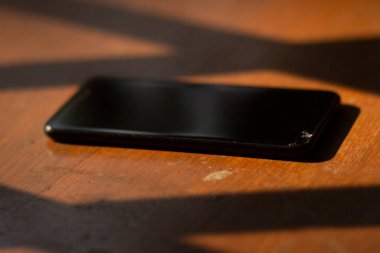 Ahşap bir masada büyük ekranlı siyah bir cep telefonu.
